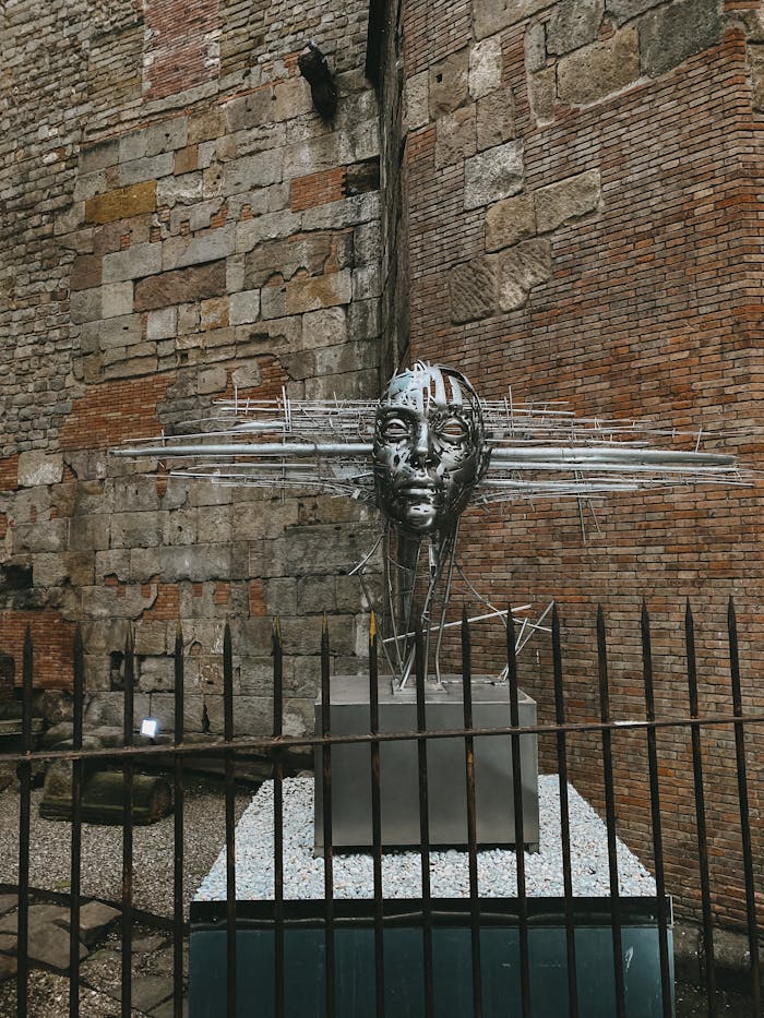 A striking metal sculpture set against an ancient brick wall highlighting urban art.